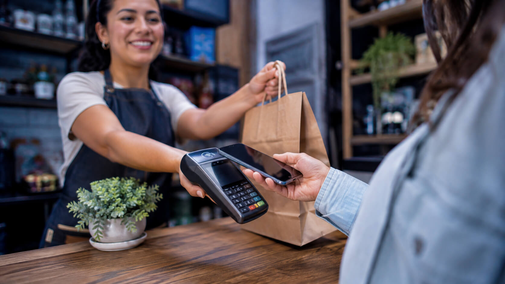 Persona pagando de forma instantánea con el celular en un comercio local